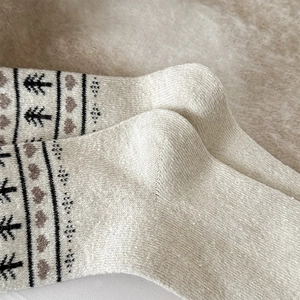 Close-up of Fair Isle wool socks with black tree and heart knitted patterns