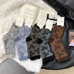 Detail of five pairs of wool crew socks with bear patterns on a soft white carpet