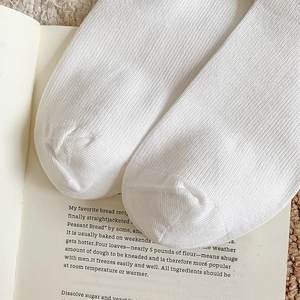 Detail of white rib-knit calf socks on a book and plush rug for cozy winter warmth
