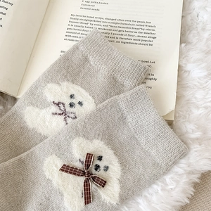 Close-up of light grey wool socks with cute white dog pattern and brown plaid bow detail