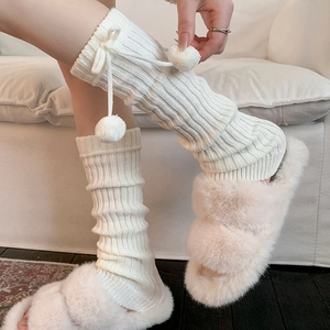 White knit leg warmers with fuzzy pom-poms and bows paired with plush slippers