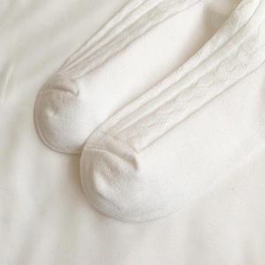 Close-up of white cable knit texture and vertical stripe pattern on over-knee socks