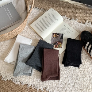 Flat lay of five pairs of ribbed cotton mid-calf socks in diverse neutral colors