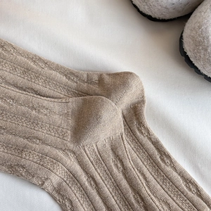 Close-up of light brown wool socks featuring vertical knit ribs and twisted cable texture