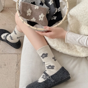 Detail of wool crew socks with floral patterns paired with Mary Jane shoes and a basket