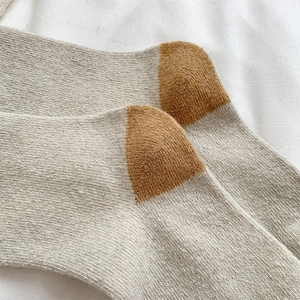 Detail of wool socks featuring oatmeal and brown color-blocking and cozy knit texture