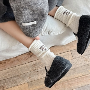 Macro shot of grey wool Mary Jane shoes with white ribbed socks and letter embroidery