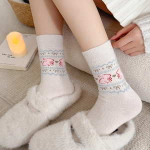 Cozy cream knit socks with pink rabbit and bow patterns shown in a warm home setting