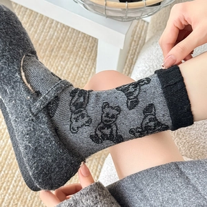 Detail of light gray wool socks with black bear pattern and dark gray felt loafers