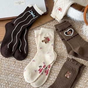 Detail of wool socks with lace trim, blue bows, and cute bear embroidery in brown tones