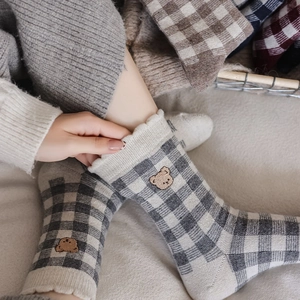 Close-up of black and white plaid socks with bear embroidery and frilled rib cuffs