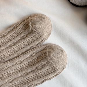Detailed macro view of khaki knit wool socks featuring vintage hollow-out vertical patterns