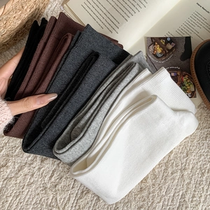 Close-up of five neutral-colored ribbed knit calf socks stacked on a soft carpet