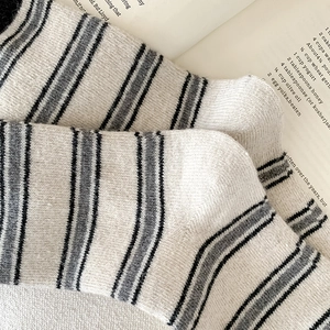 Gros plan détaillé de chaussettes en laine à rayures grises et noires sur tricot crème