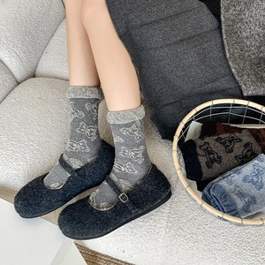 Close-up of gray wool socks with white bear pattern and fuzzy Mary Jane flats