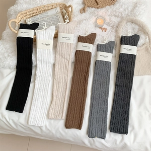 Flat lay of six pairs of knit cable patterned over-knee socks in various neutral colors