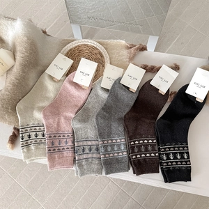 Detail of wool socks with heart and tree patterns in warm neutral tones for winter