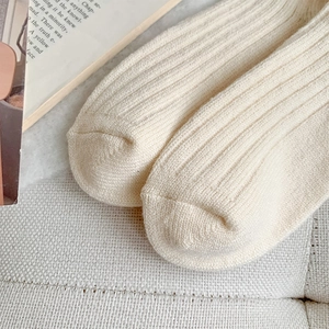 Detailed close-up of cream ribbed knit long socks with soft autumn texture
