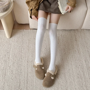 Close-up of white cable knit over-the-knee socks with vintage texture and loafers