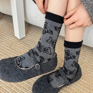 Detail of wool socks with bear pattern and Mary Jane shoes on a cozy carpet