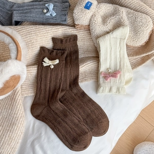 Detailed knit texture of wool mid-tube socks with elegant bow and pearl accents