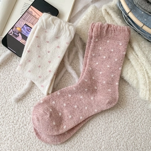 Detailed knit texture of thick polka dot wool socks in cream and dusty rose pink