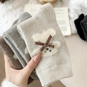 Detail showing plush bear patch and checkered bow on cozy knitted crew socks