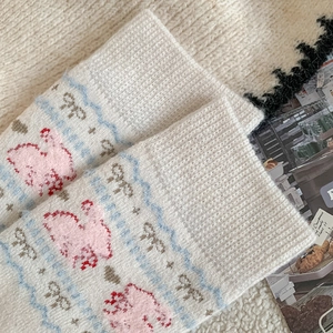 Detailed close-up of cozy knitted socks with cute pink rabbit and blue wave patterns