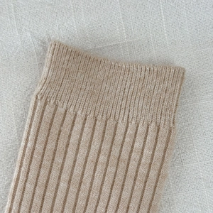 Detailed macro view of the soft ribbed knit texture on warm beige slouch socks