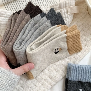 Close-up of cozy wool blend socks featuring cute cartoon dog embroidery and ribbed cuffs