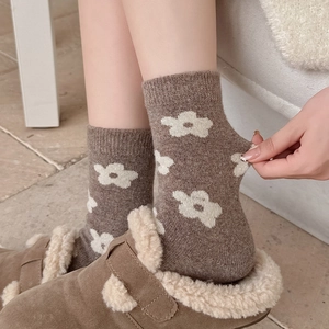 Close-up of thick coffee wool sock with white flower pattern and elastic knit texture