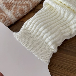 Macro detail of white wavy rib knit fabric showing soft texture and thick knit pattern
