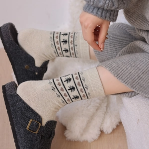 Close-up of Fair Isle wool socks with heart and tree patterns worn with fuzzy slippers