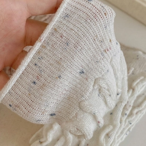 Détail de chaussettes en laine blanche en maille torsadée avec points colorés et bord côte