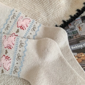 Detail of cream knit socks with pink rabbit and blue wave patterns in cozy setting