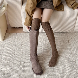 Close-up of brown knit over-knee socks paired with stylish matte leather boots for winter