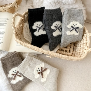 Detail of wool socks featuring 3D plush puppy and plaid bow in five earthy tones