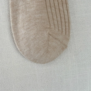 Macro detail of oatmeal ribbed knit socks showing high-quality seamless toe stitching