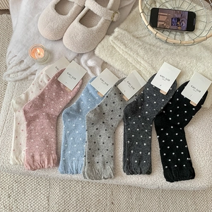 Detailed view of cozy polka dot knit socks in six colors on a textured home rug