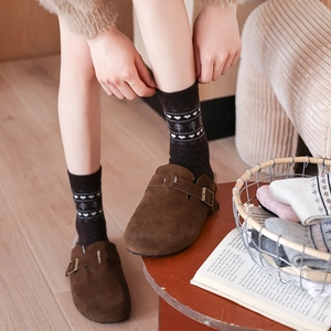 Detail of wool Fair Isle socks with tree patterns worn with brown suede clogs