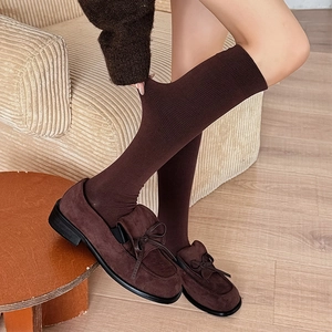 Detail of dark brown knee high socks with vertical ribbed knit texture and loafers