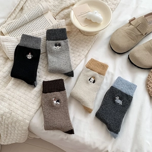 Detail of five pairs of warm wool socks with cute animal embroidery in cozy home setting