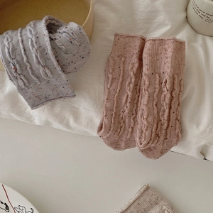 Détail de chaussettes en laine à torsades avec fils mouchetés et texture côtelée douce