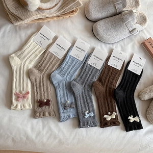 Detail of wool socks with ribbon bows, pearls and ruffle cuffs in six neutral colors