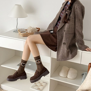 Detail of brown wool socks featuring cute bear embroidery and white lace heart trim