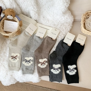 Close-up of five pairs of thick wool socks with 3D teddy bears and plaid bows
