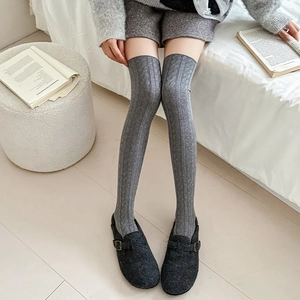 Detailed texture of grey cable knit over-the-knee socks with stylish wool shoes