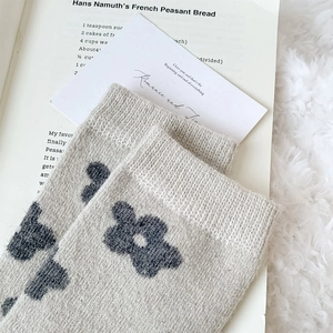Macro view of grey wool socks with knit floral patterns on a cozy winter background