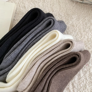 Detail of ribbed knit wool blend calf socks in five colors on soft white carpet background