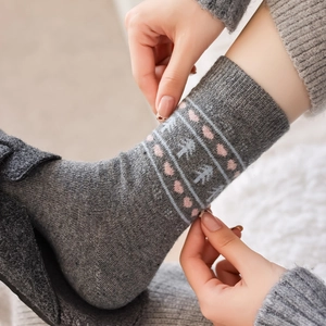 Detail of wool socks showing pink heart and geometric tree jacquard knit patterns